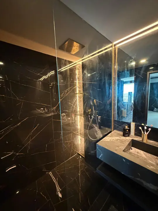 Black marble bathroom with mirror, LED lighting and shower screen