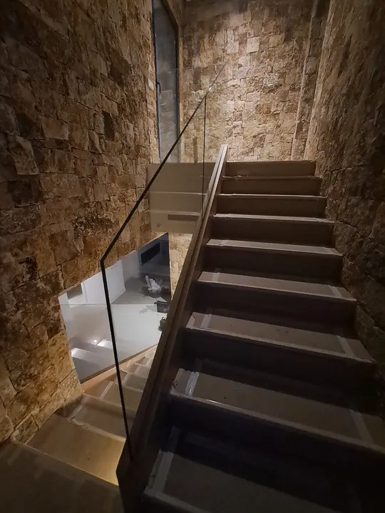 Glass balustrade on a staircase with a stone wall