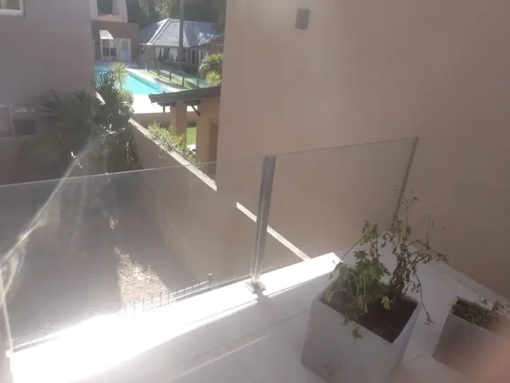 Glass balustrade on a terrace with a garden and pool
