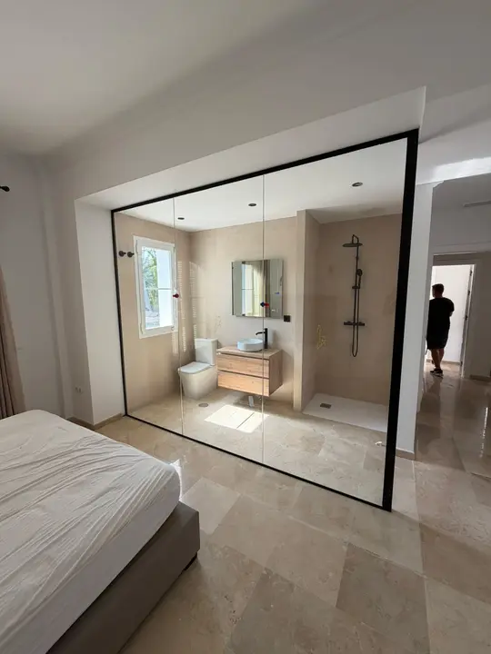 Floor-to-ceiling glass enclosure between bedroom and bathroom