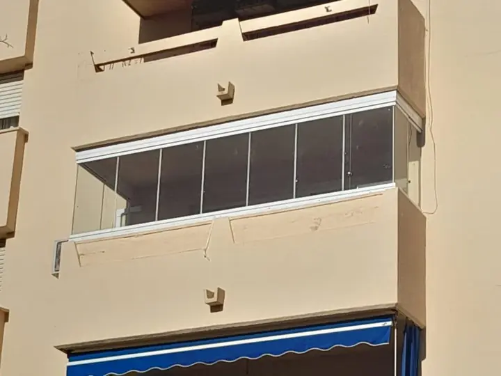 Façade with a balcony enclosed by glass curtains