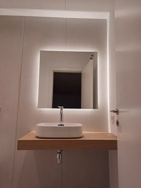 Square LED mirror above a wooden washbasin