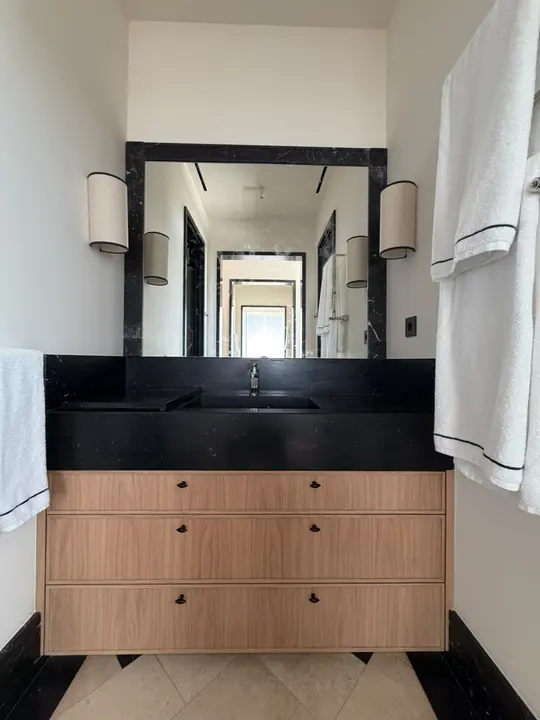 Black-framed mirror with wall lights in a black marble bathroom