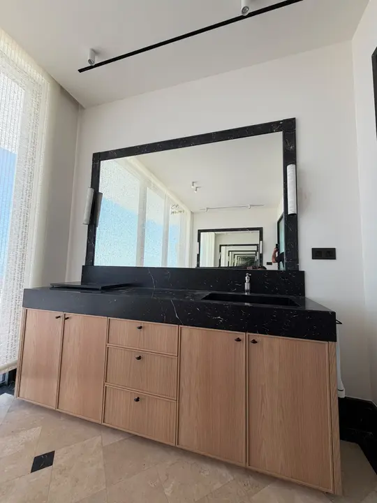 Black-framed mirror above a marble and wood washbasin