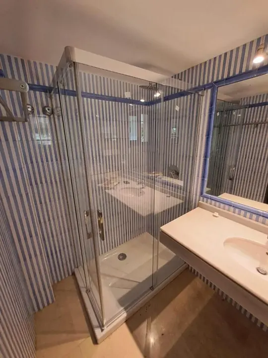 Corner glass shower screen in a bathroom with striped tiles