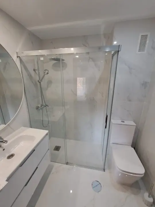 Sliding glass shower screen in a white marble bathroom
