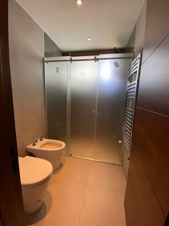 Sliding glass shower screen in a bathroom with wood