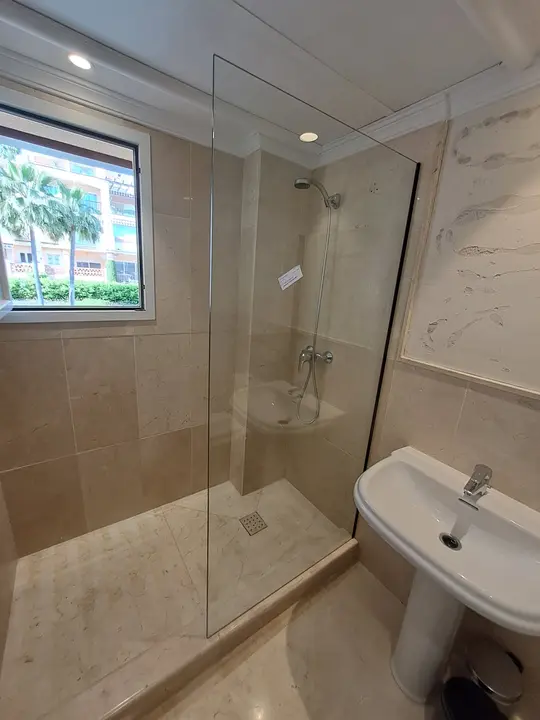 Fixed glass shower screen beside a window
