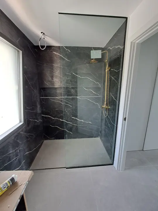 Fixed shower screen in a black marble shower