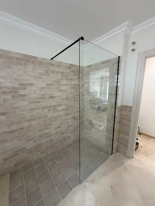 Walk-in shower screen with a black profile in a tiled shower